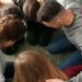 A group of young people hugging each other and praying